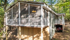 A wooden deck with a railing, a covered porch, and a small enclosed area with a ladder. - Cozy cabin w/ Screened porch & BBQ (Hedgesville)
