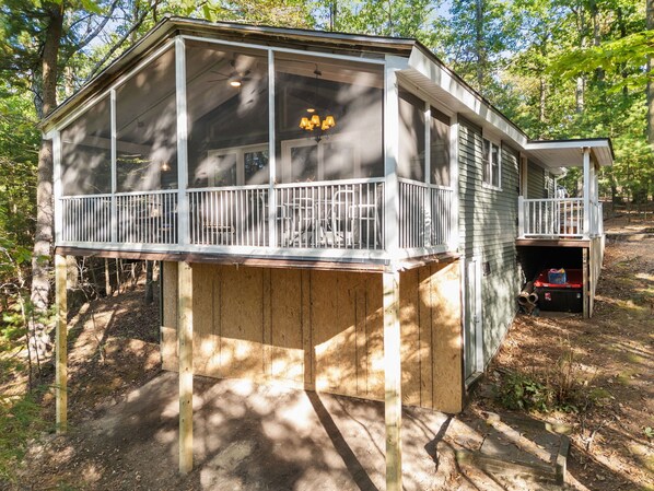 A wooden deck with a railing, a covered porch, and a small enclosed area with a ladder. - Cozy cabin w/ Screened porch & BBQ (Hedgesville)