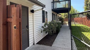 Ein zweistöckiges Wohnhaus mit überdachter Veranda, einem Holztor und einem eingezäunten Hinterhof.