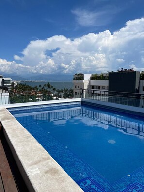 A rooftop swimming pool with a clear view of the ocean and cityscape. - Life Bucerías: Modern Studio Near the Beach (Bucerías)