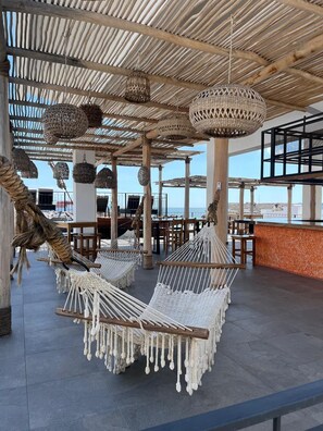 Een terras op het dak met macramé hangstoelen, wilgentwillichtjes en een bar.