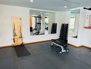A gym with a bench, weight racks, and exercise equipment. - Life Bucerías: Modern Studio Near the Beach (Bucerías)