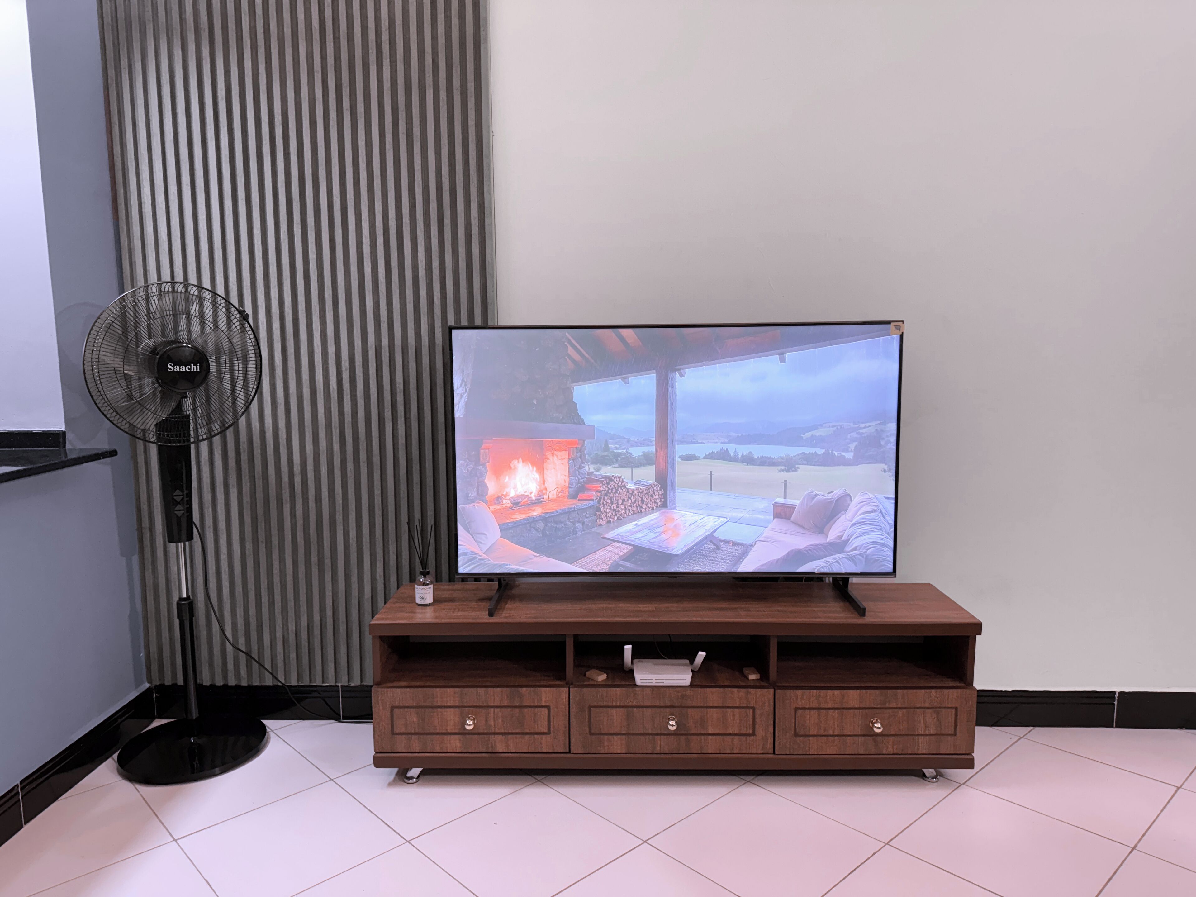 A flat-screen TV on a wooden TV stand with a view of a fireplace and outdoor scenery.