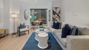 Un salon moderne avec un canapé, une table basse et des fauteuils. On y trouve également une table à manger avec des chaises et une lampe.