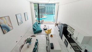 A modern interior with a living area, dining space, kitchen, and a view of an outdoor swimming pool. - Unique Townhouse Pool Slide Access (Bophut)