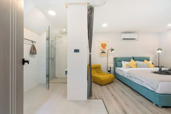 A modern bedroom with a bed, a yellow chair, and a shower area. - Unique Townhouse Pool Slide Access (Bophut)