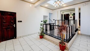 Ένας ευρύχωρος εσωτερικός χώρος με σκάλα, φυτά σε γλάστρες και φεγγίτη.