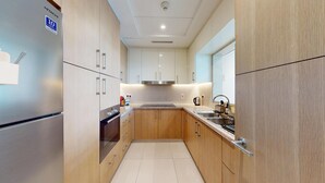 Une cuisine moderne dotée d’appareils électroménagers en acier inoxydable, de meubles en bois et d’un dosseret carrelé.
