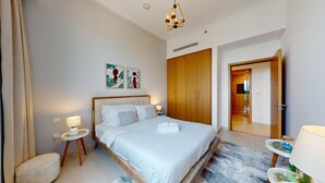 Une chambre d’hôtel avec un grand lit, une armoire en bois et une salle de bain visible à travers une porte ouverte.