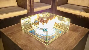 A square coffee table with a glass top and a central fire feature, surrounded by two sofas with cushions. - Yosemite/Bass Lake Oasis – Modern Furnishings, Hot Tub, Game Room, EV Plug, BBQ & Fire Pit, Pet‑Friendly | Sleeps 19+ | 5 Mins to Downtown (Oakhurst)