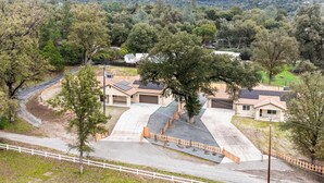 A residential area with houses, a curved driveway, and a white fence. - Yosemite/Bass Lake Oasis – Modern Furnishings, Hot Tub, Game Room, EV Plug, BBQ & Fire Pit, Pet‑Friendly | Sleeps 19+ | 5 Mins to Downtown (Oakhurst)