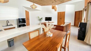 A modern kitchen with a wooden dining table, built-in appliances, and a ceiling fan. - Maravilla two bedrooms with garden view (Bali)