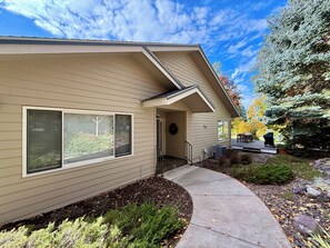 A two-story house with a covered porch, a front door, and a small deck.