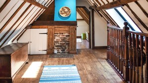 A loft-style room with exposed wooden beams, a blue accent wall, and a patterned rug. - 2 bedroom accommodation in Kings Lynn (Kings Lynn)