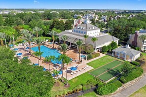 An aerial view of a resort with a swimming pool, sun loungers, and a well-maintained lawn. - Condo with Golf Course Views & Close Pool Access (Kissimmee)