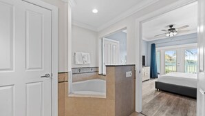 Une salle de bain moderne équipée d’une baignoire, d’une douche et d’un meuble-lavabo. Une grande fenêtre offre une vue sur l’extérieur.