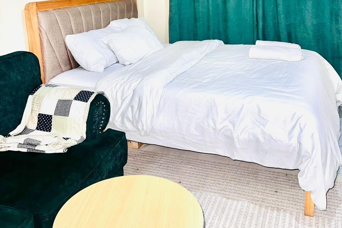 Ein ordentlich eingerichtetes Hotelzimmer mit Bett, Sessel und rundem Tisch.