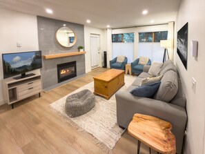 A modern living room with a fireplace, a television, a sofa, and a coffee table.