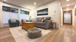 Una sala de estar moderna con sofá, sillones, una mesa de centro y alfombra.