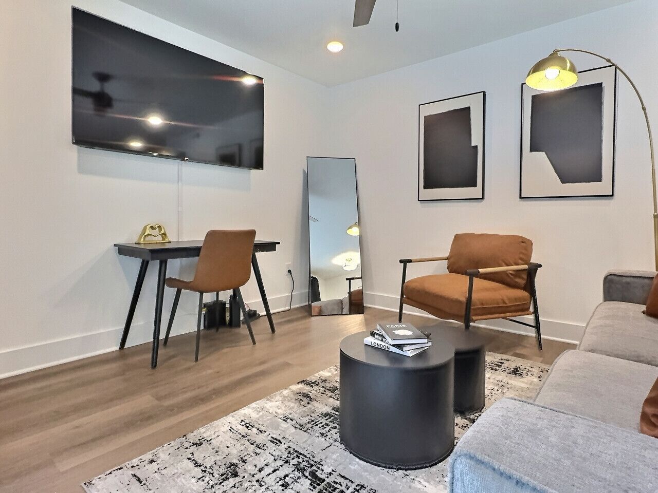 Una sala de estar moderna con comedor, un espejo grande y un ventilador de techo.