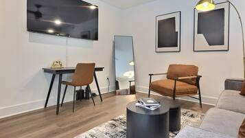 Una sala de estar moderna con comedor, un espejo grande y un ventilador de techo.