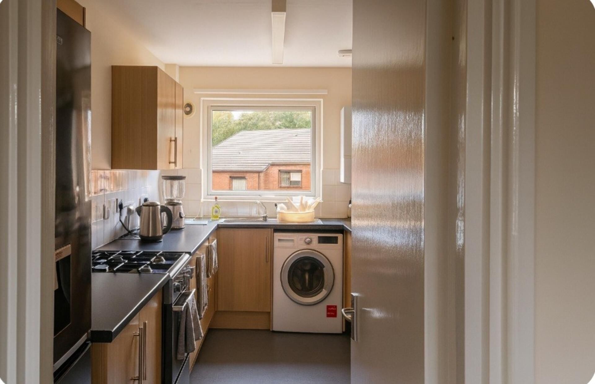 A compact kitchen with a stove, sink, and washing machine.