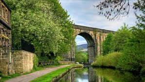 Un pont de pierre enjambant un canal, avec un chemin de promenade d’un côté et un bâtiment de l’autre.