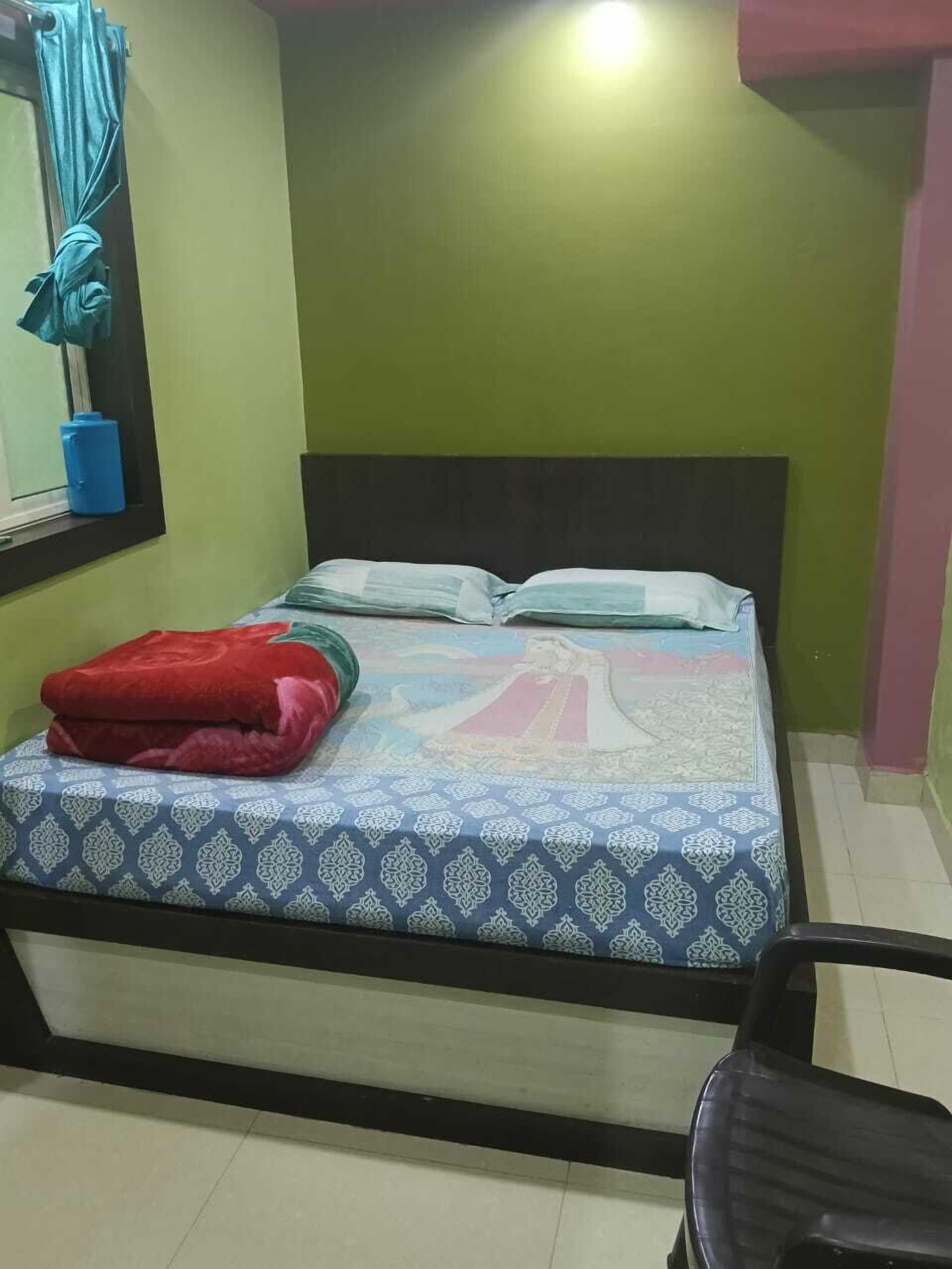 A room with a bed, a chair, a window with curtains, and a wall with a green and pink color scheme.