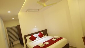 A modern hotel room with a large bed, a ceiling fan, and a small air conditioning unit. - Airport Avenue Plaza (Nedumbassery)