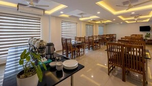 A spacious dining area with multiple tables and chairs, ceiling fans, and a modern design. - Airport Avenue Plaza (Nedumbassery)