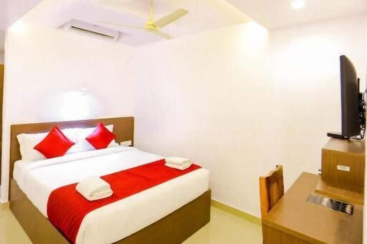 A hotel room with a bed, a desk, a television, and a ceiling fan.