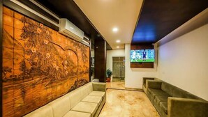 A modern lobby with a marble floor, a large wall mural, and a seating area. - Airport Avenue Plaza (Nedumbassery)