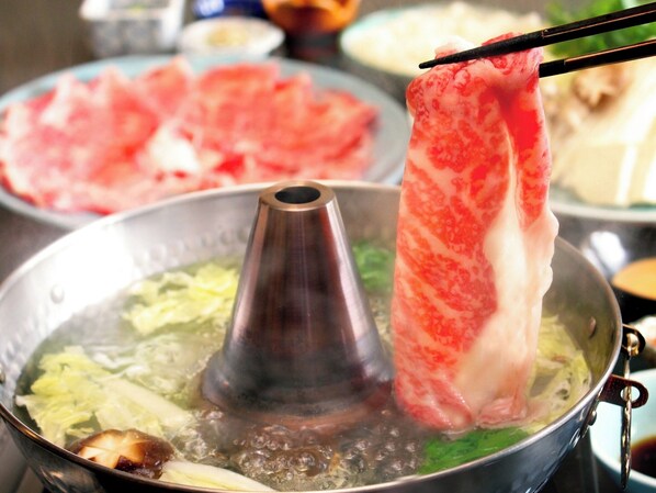 Ein heißes Pot mit verschiedenen Zutaten, darunter Fleisch und Gemüse, wird zubereitet.