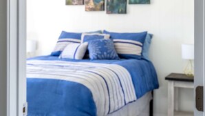 Une chambre à coucher avec un lit, une table de chevet et un tableau accroché au mur.