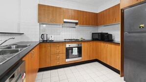 Une cuisine moderne avec des meubles en bois, des appareils électroménagers en acier inoxydable et un dosseret carrelé.