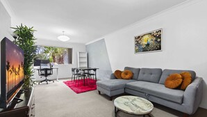 Un salon moderne avec un canapé gris, une table basse ronde et un tableau accroché au mur.