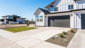 Ein modernes, zweistöckiges Haus mit Garage, gepflegtem Rasen und befestigter Auffahrt.