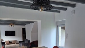 A modern dining area with a wooden table, black and red chairs, and a hanging light fixture. - Renovated house on the Route des Châteaux (Saché)