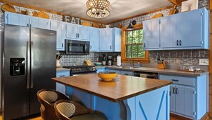 A modern kitchen with blue cabinets, stainless steel appliances, and a central island.