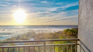 Un balcón con vista al océano y a la playa al atardecer.