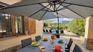 An outdoor dining area with a table set for four, surrounded by chairs, under a large umbrella. - Casa Marsa - Calonge, Catalonia (Calonge)