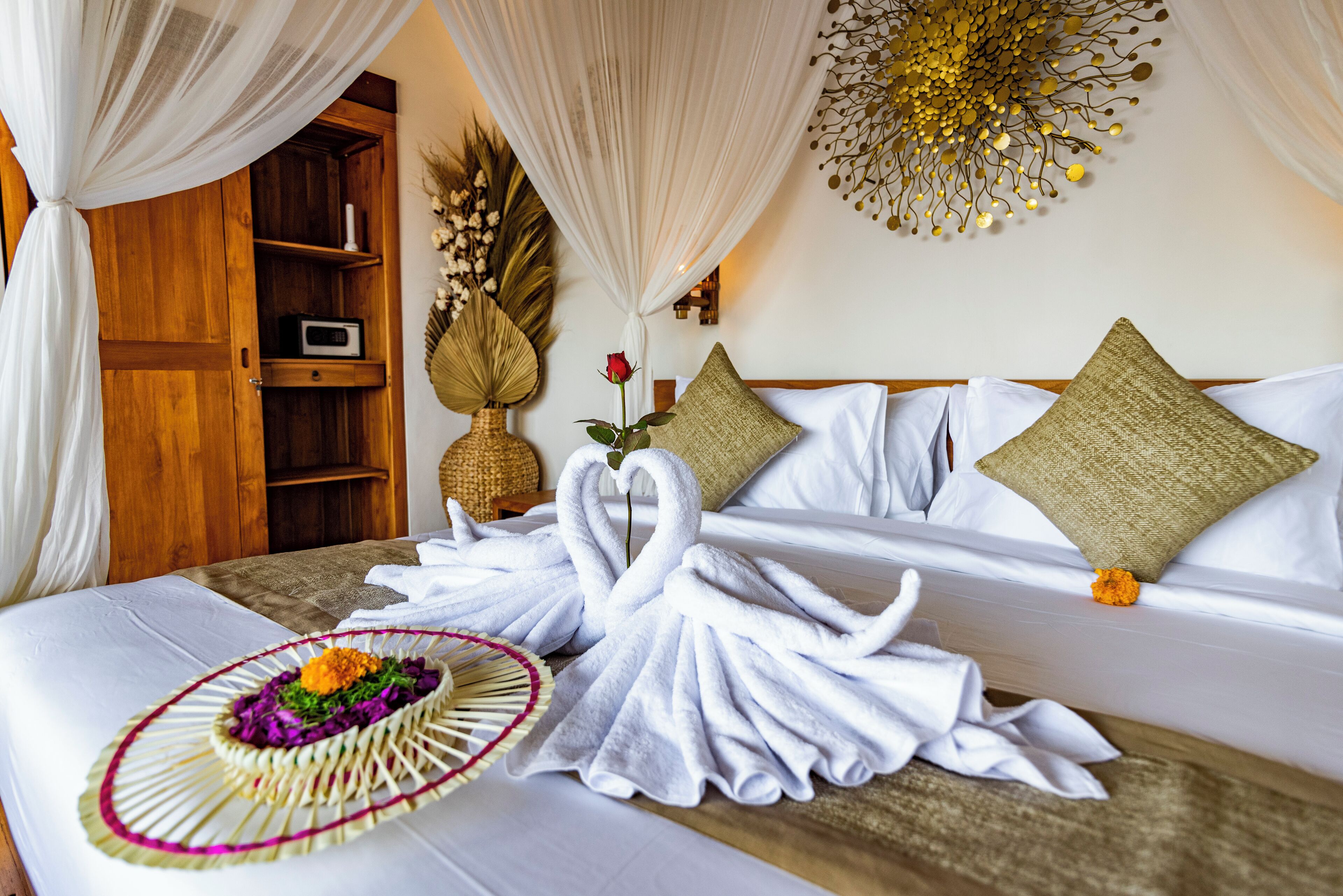 A hotel room with a bed, a wooden cabinet, a decorative wall piece, and a bouquet of flowers.