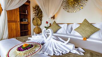 A hotel room with a bed, a wooden cabinet, a decorative wall piece, and a bouquet of flowers.