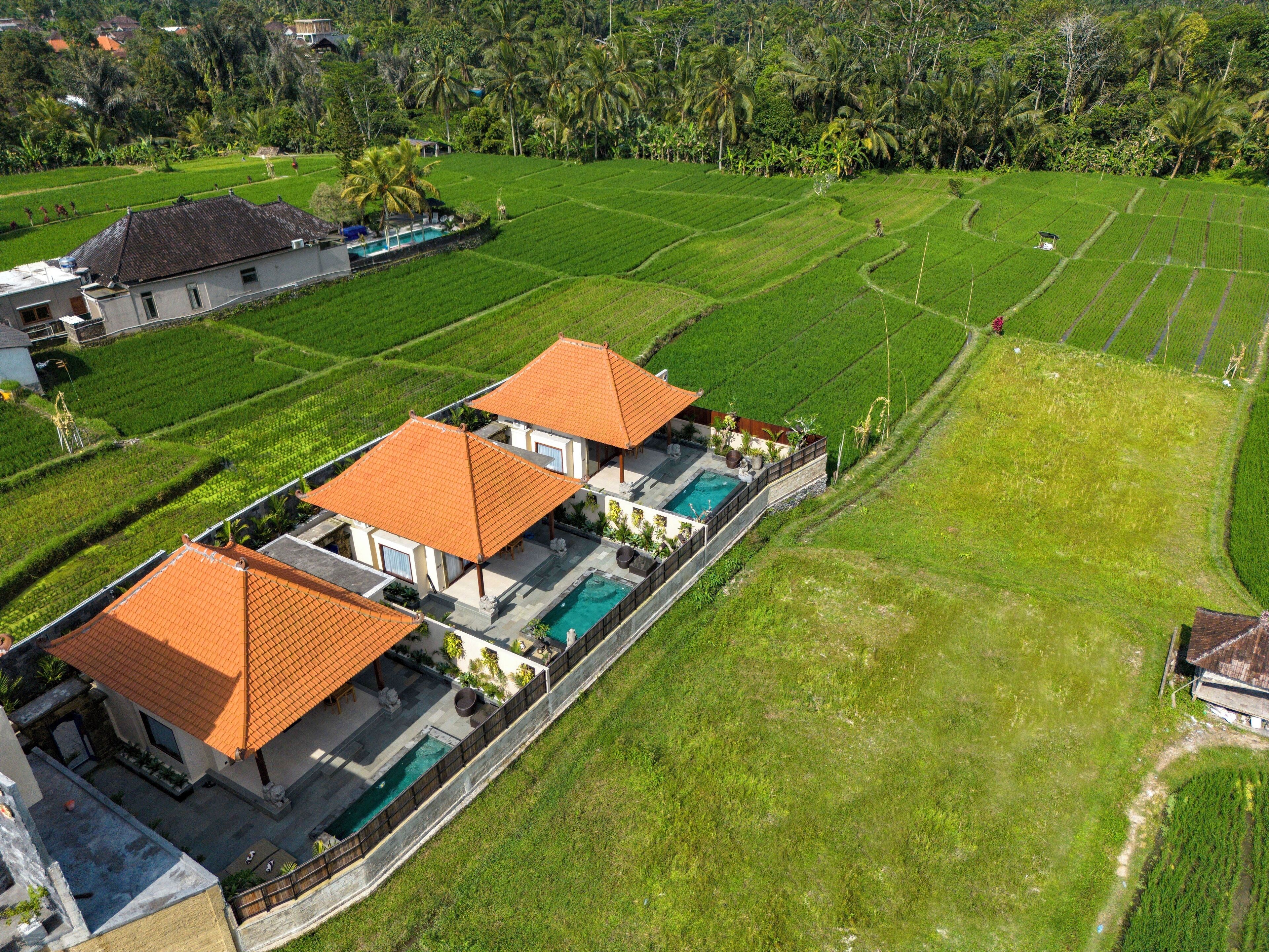 A large house with a swimming pool and a view of the surrounding lush green fields.