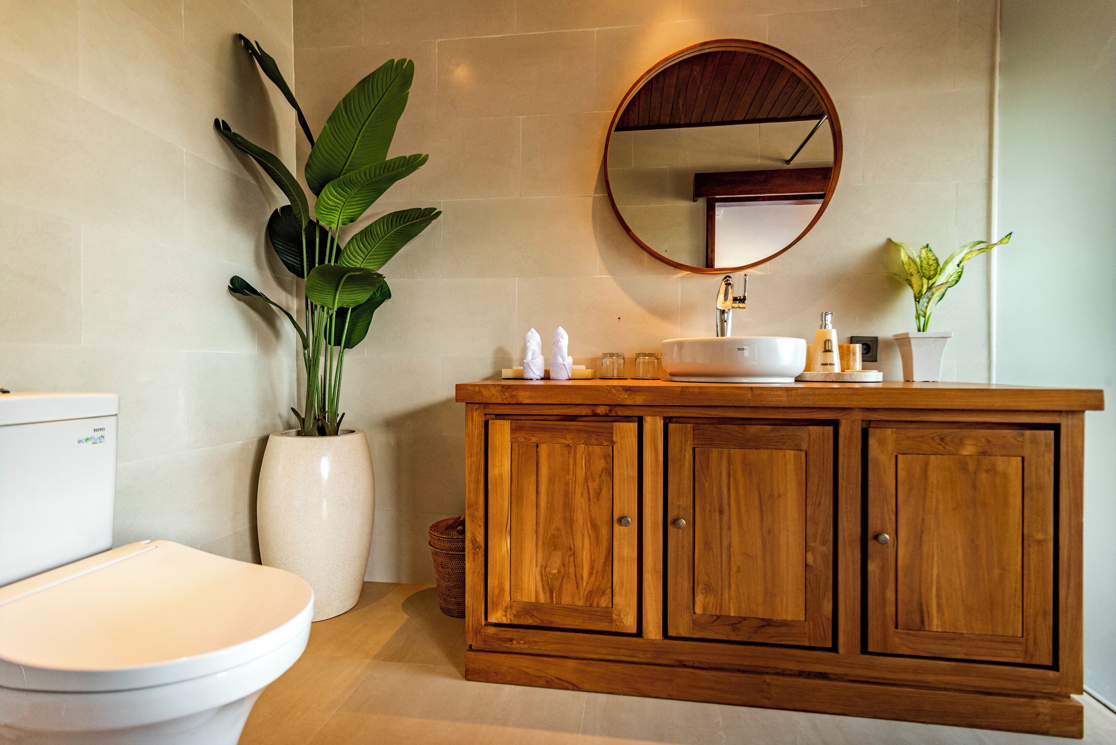 Un baño con inodoro, tocador de madera con lavabo y un espejo grande.