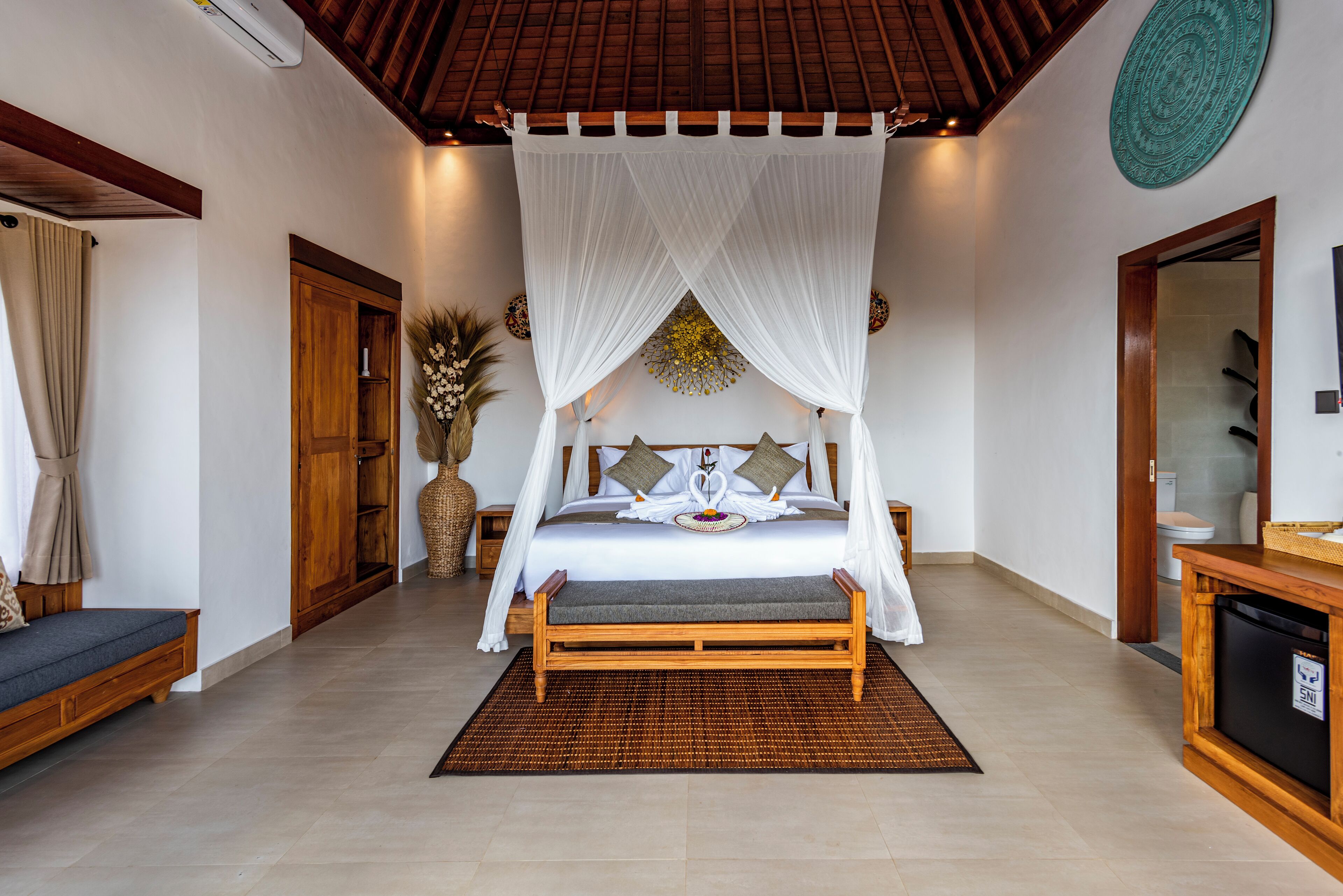 A bedroom with a wooden bed, white canopy, and a small wooden cabinet.