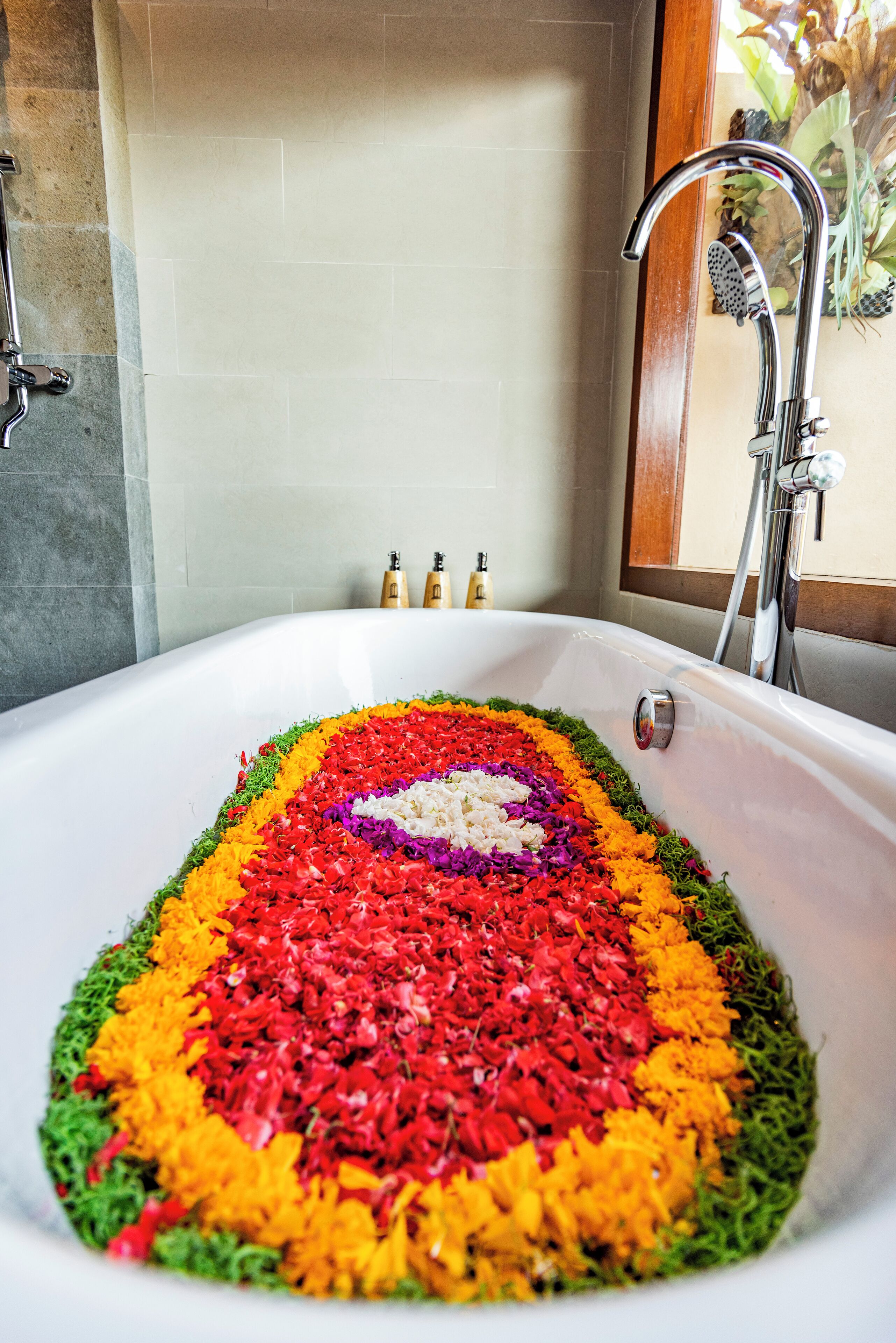 A bathtub filled with colorful flower petals arranged in a pattern.