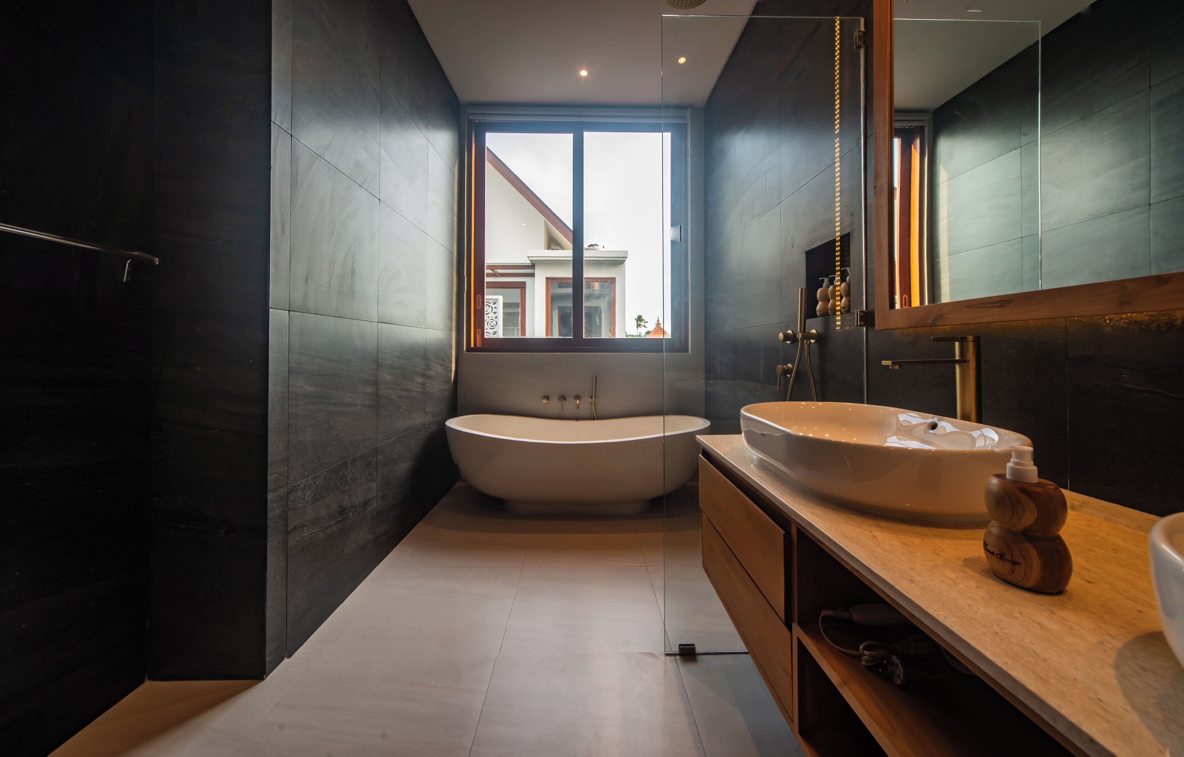 A modern bathroom with a freestanding bathtub, a large vanity with a sink, and a mirror.