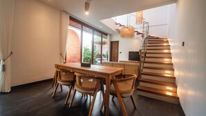 Une cuisine moderne avec une table et des chaises en bois, un escalier dont les marches sont illuminées, et une vue sur la verdure à l’extérieur.
