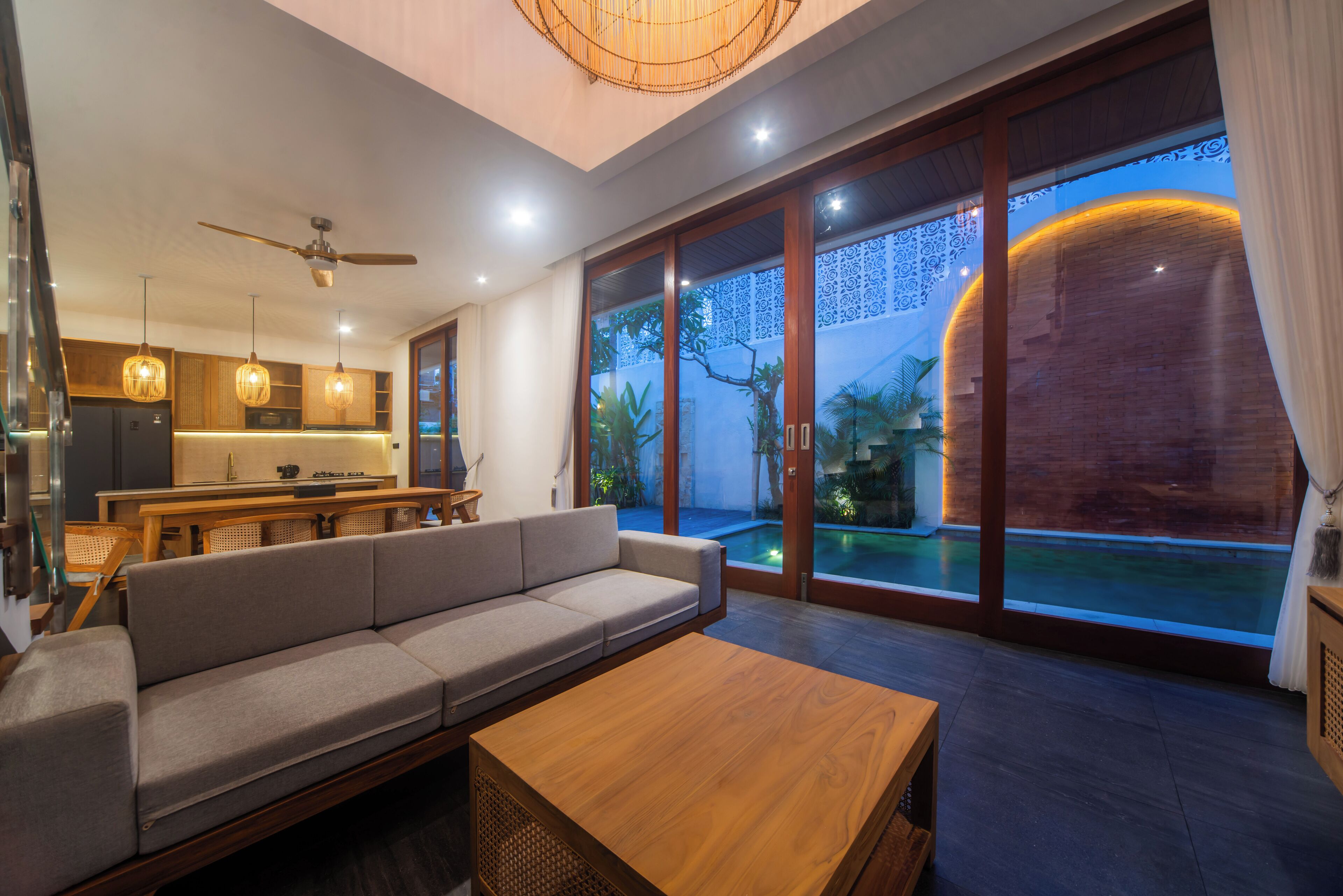 A modern living room with a sofa, wooden coffee table, and a dining area with a kitchen in the background.